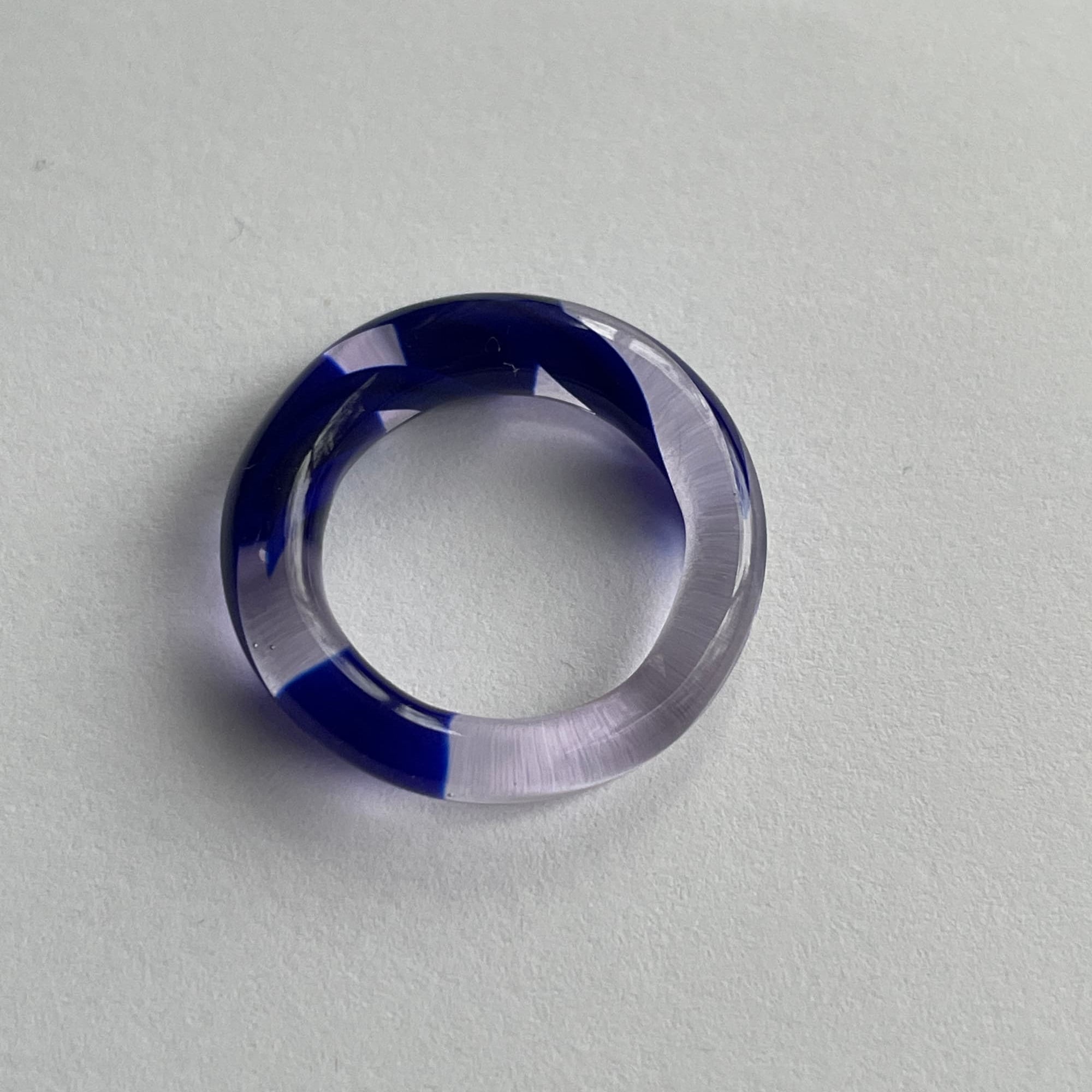 Glass Ring from All Rivers, clear  purple ring with blue inlay on a light gray background