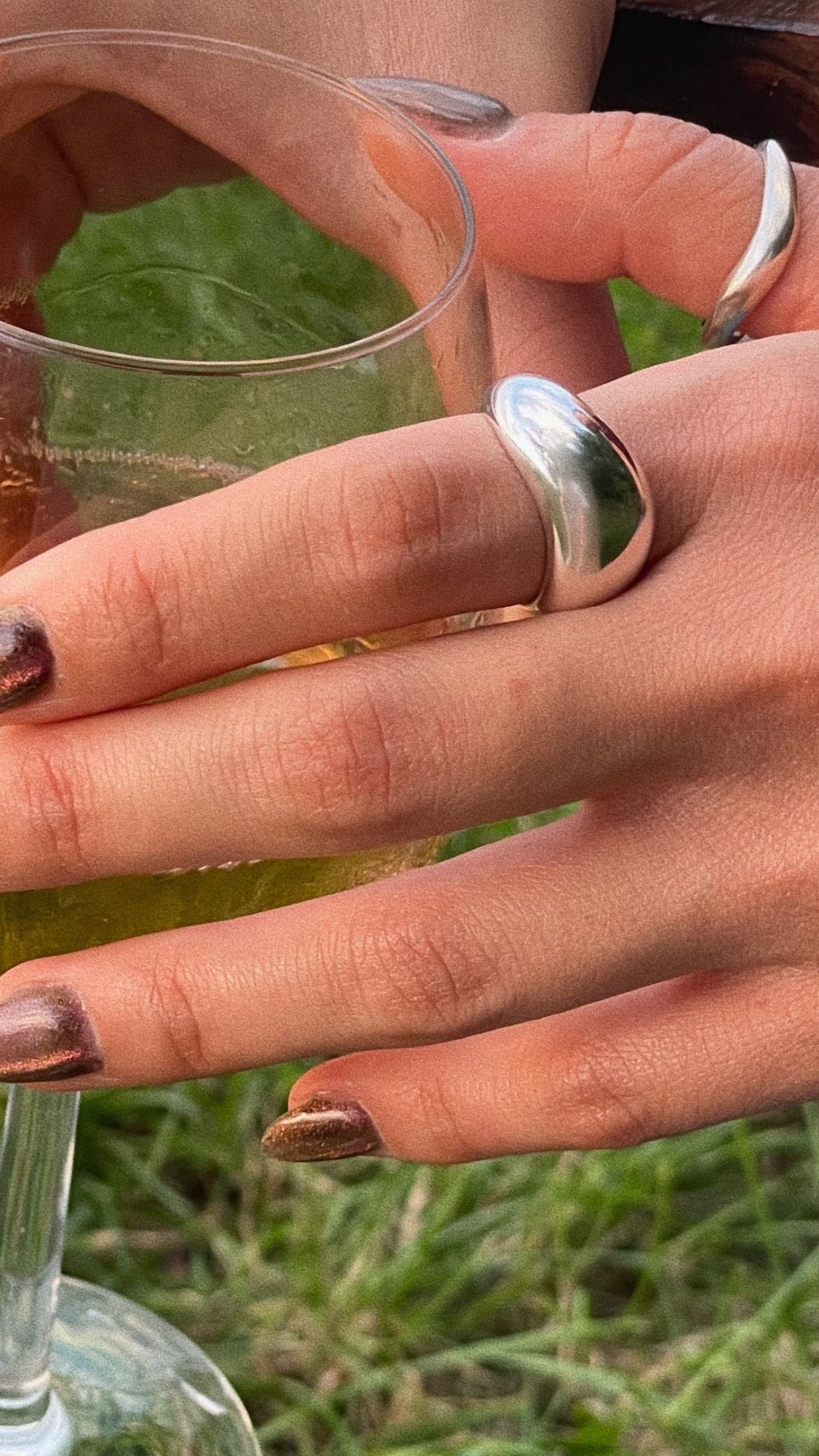 All Rivers sterling silver ring worn by woman hand holding glass