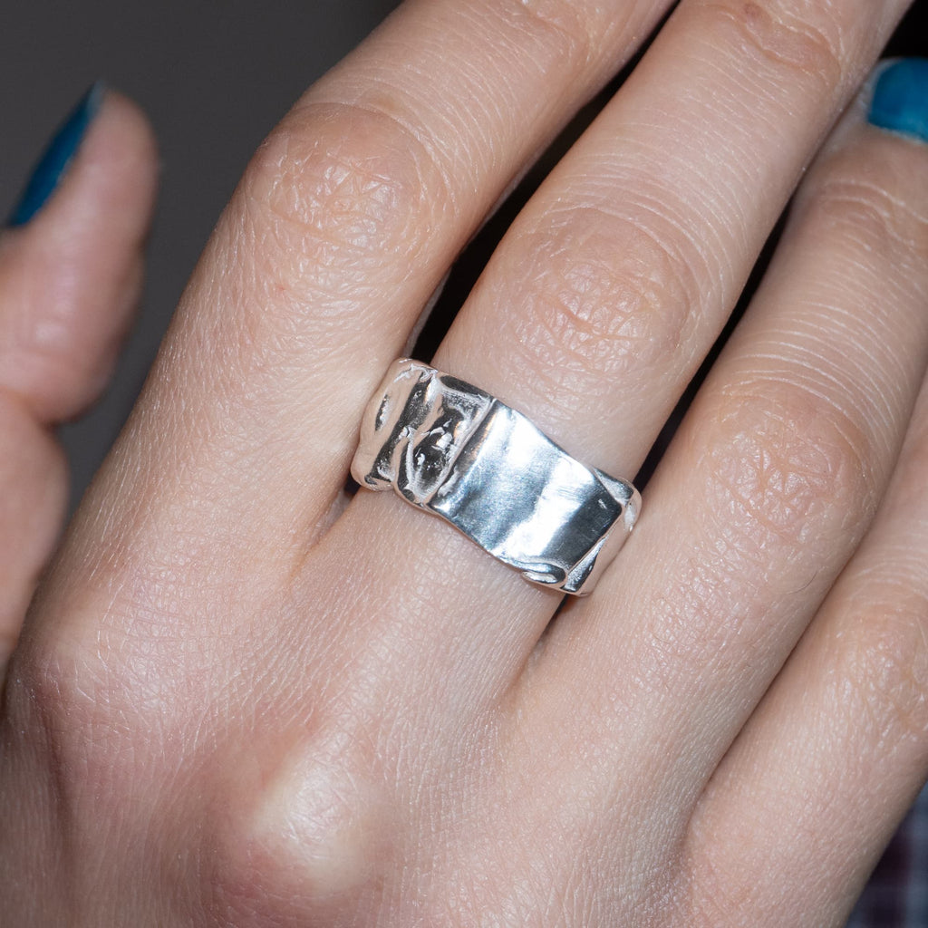 Silver ring on a person's finger with a neutral background