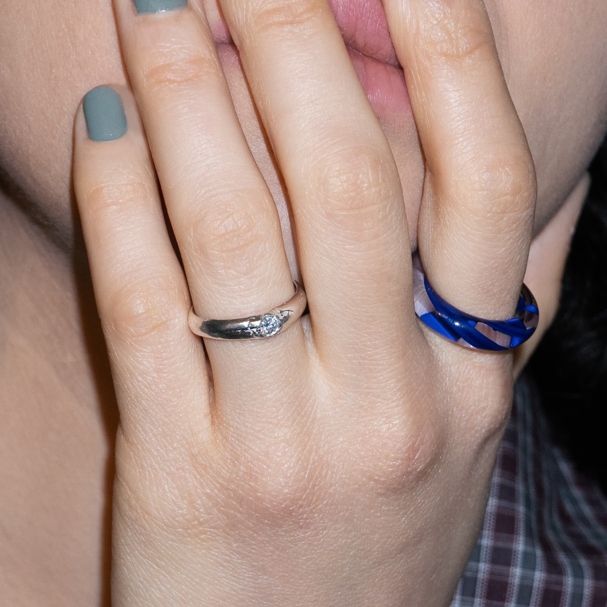 Close-up of a hand wearing two rings with a blurred background