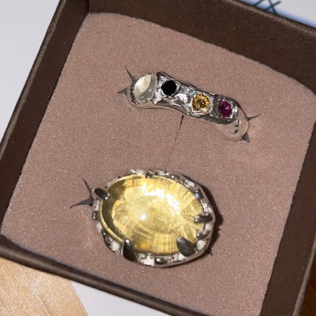 Two jewelry pieces in a box on a wooden surface