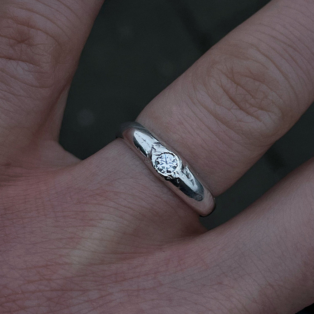 Silver ring from All Rivers with a moissanite on a person's finger